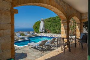 ストウパにあるSOFIA, Luxury Stone Villa in Stoupa with Private Pool, BBQ and Amazing Sea Viewのプールと椅子とアーチのあるパティオ