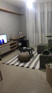 a living room with a couch and a table and a tv at Amplo Quarto e sala decorado in Salvador