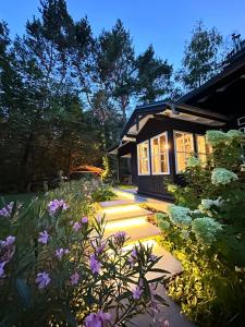 a garden with purple flowers in front of a house at Joy Village in Warsaw