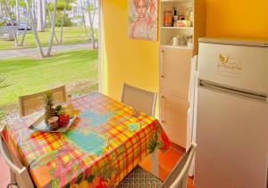 a small kitchen with a table and a refrigerator at Chaleureux studio 4 personnes - Résidence Anse des Rochers - " Les Alizés du soir " Tout équipé et citerne d'eau in Saint-François