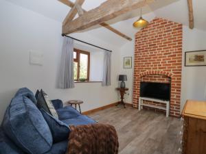 sala de estar con sofá azul y chimenea de ladrillo en Keepers Barn en Worcester