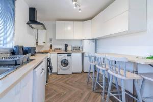 a kitchen with white cabinets and white appliances at The Amazing Welsh Oasis! in Newport