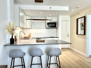 a kitchen with two bar stools and a counter at High-End Apartment, Across the Beach in Miami Beach