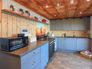 a large kitchen with blue cabinets and a microwave at Doune Bay Lodge in Mallaig