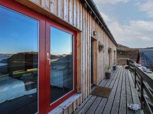 a house with a red door on a wooden deck at Doune Bay Lodge in Mallaig