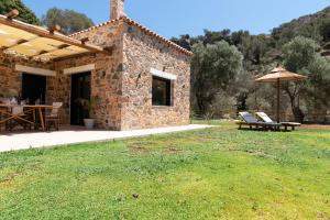 a stone house with a picnic table and an umbrella at Aoria Villas in Palaiochóra