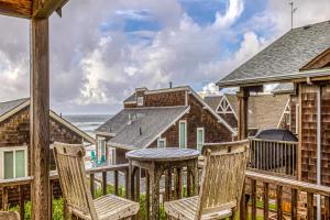 una terraza con sillas, una mesa y el océano en Cannon Beach Saltbox Cottage en Cannon Beach