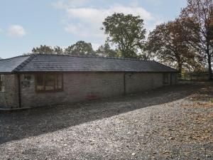 a small brick building with a gravel road in front at The Cow Shed in Worcester