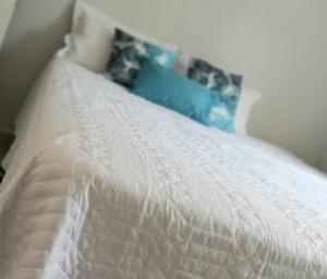 uma cama branca com um edredão branco em Apto c/ Ar Wifi Suite Garagem Shopping em Taubaté