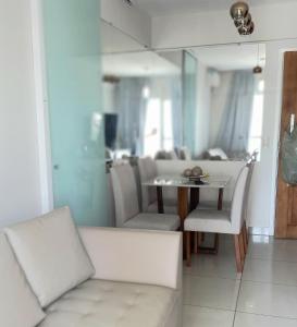 uma sala de estar com uma mesa e cadeiras brancas em Apto c/ Ar Wifi Suite Garagem Shopping em Taubaté