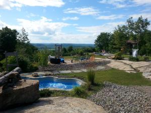 a small pond in a yard with a playground at Éco Spa Highland in Grenville-sur-la-Rouge