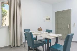 Vibe 305, Modern 2Bedroom Apartment in Awkar في Dbayeh: غرفة طعام مع طاولة بيضاء وكراسي زرقاء