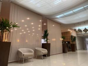 a lobby with two chairs and lights on the wall at Santa Catarina Plaza Hotel in Canoinhas