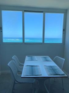 stół i krzesła w pokoju z dwoma oknami w obiekcie KASA Blue Ocean - 2 bed 2 bath for 4 OCEAN VIEW BALCONY BEACHFRONT CONDO POOL w mieście San Juan