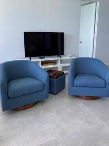 two blue chairs in a living room with a tv at KASA Blue Ocean - 2 bed 2 bath for 4 OCEAN VIEW BALCONY BEACHFRONT CONDO POOL in San Juan