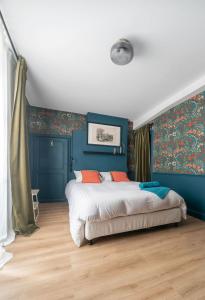 um quarto com paredes azuis e uma cama com almofadas laranja em Grande Maison Cusset - Maison de ville - 3 chambres em Cusset