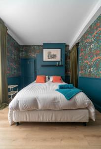 een slaapkamer met blauwe muren en een bed met oranje kussens bij Grande Maison Cusset - Maison de ville - 3 chambres in Cusset