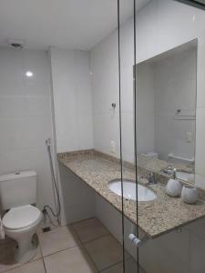 Baño blanco con aseo y lavamanos en Aconchego da Prainha dois quartos, ar condicionado, wifi , duas vagas de garagem, en Arraial do Cabo