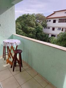 un balcón con 2 taburetes y una mesa en una cornisa en Aconchego da Prainha dois quartos, ar condicionado, wifi , duas vagas de garagem, en Arraial do Cabo