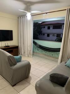 sala de estar con sofá y TV de pantalla plana en Aconchego da Prainha dois quartos, ar condicionado, wifi , duas vagas de garagem, en Arraial do Cabo