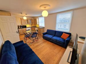 uma sala de estar com um sofá azul e uma cozinha em Cosy Home in Kensington - 2 minutes to Subway/Tube - Ealrs Court Station em Londres