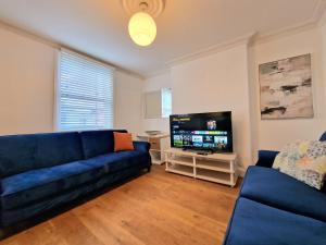 uma sala de estar com um sofá azul e uma televisão de ecrã plano em Cosy Home in Kensington - 2 minutes to Subway/Tube - Ealrs Court Station em Londres