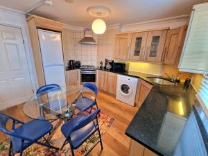 uma cozinha com uma mesa de vidro e cadeiras azuis em Cosy Home in Kensington - 2 minutes to Subway/Tube - Ealrs Court Station em Londres
