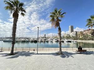 a man sitting on a bench next to a marina at Donoso Cortes Apartment - Alicante in Alicante