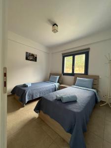 a bedroom with two beds and a window at Aegean Mirror, Andros in Apróvaton