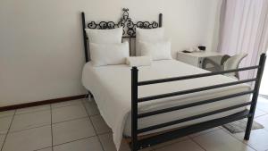 1 dormitorio con 1 cama con sábanas y almohadas blancas en New Lodge, en Bloemfontein