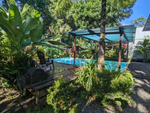 a swimming pool in a garden with a blue umbrella at Arboura Eco Cabins in Uvita
