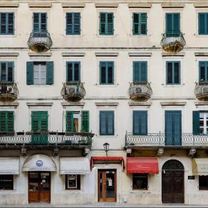 ein hohes weißes Gebäude mit grünen Rollläden und Balkonen in der Unterkunft Hive Luxury Suites Collection in Kotor