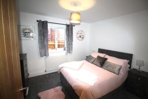 a bedroom with a bed with pink pillows and a window at Rawmarsh - 2 Bedroom Bungalow - Brand New Build - High End Furnishings - Large Enclosed Garden in Rotherham