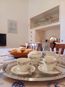 einen Tisch mit drei Teetassen und Untertassen darauf in der Unterkunft Casa Ciusa in Quartu SantʼElena