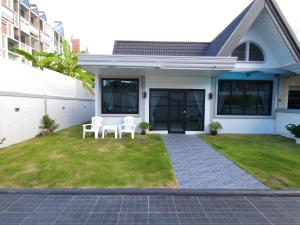 une maison avec 2 chaises blanches sur la pelouse dans l'établissement Tawan House, à Pattaya (nord)
