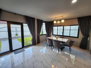 a dining room with a table and chairs and windows at Tawan House in North Pattaya