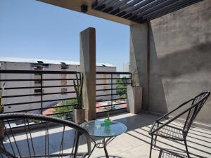 patio con mesa de cristal y sillas en el balcón en Comodo Dpto con Balcon & wifi en Santiago del Estero