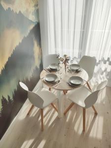 ein Esszimmer mit einem Tisch und weißen Stühlen in der Unterkunft White Apartament Szklarska Poręba in Szklarska Poręba