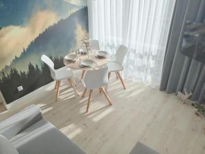 ein Esszimmer mit einem Tisch und weißen Stühlen in der Unterkunft White Apartament Szklarska Poręba in Szklarska Poręba