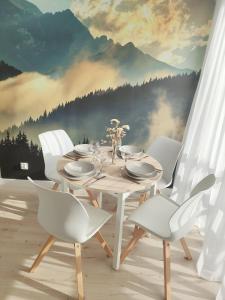 斯克拉斯卡波伦巴White Apartament Szklarska Poręba的一间带桌子和白色椅子的餐厅