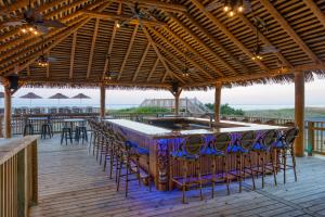 eine Bar mit Stühlen und Tischen auf einer Terrasse in der Unterkunft Ramada Plaza by Wyndham Nags Head Oceanfront in Kill Devil Hills