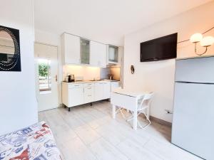 - une cuisine avec des placards blancs, une table et un réfrigérateur dans l'établissement T2 Mer 50m - Clim YourHostHelper, à Bormes-les-Mimosas