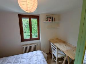 1 dormitorio con cama, escritorio y ventana en Appartement avec vue sur le Sancy, parking gratuit, en Le Mont-Dore