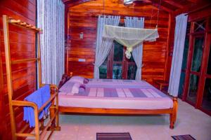 a bedroom with a bed in a wooden house at Sinharaja Rest in Deniyaya