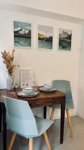 a dining room table with two chairs and paintings on the wall at Le Chalet de la Plage in Sévrier