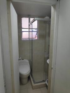 een badkamer met een toilet en een glazen douche bij Habitación privada tipo hotel, Baño, TV y WiFi. in Bogota