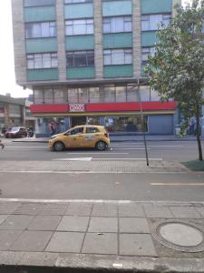 een gele taxi die door een straat rijdt voor een gebouw bij Habitación privada tipo hotel, Baño, TV y WiFi. in Bogota