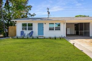 ein weißes Haus mit einer blauen Tür und einem Hof in der Unterkunft Boho Villa 10 mins from Siesta in Sarasota