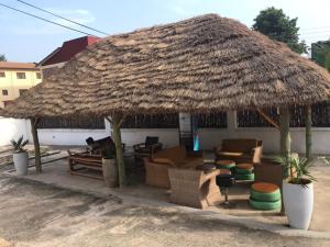 a straw hut with chairs and a dog sitting under it at Nana's Holiday Let in Accra