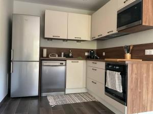a kitchen with white cabinets and a stainless steel refrigerator at Cottage Sainte Marguerite in Gap